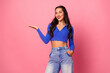 © deagreez - Young chic model in blue crop top and jeans stands against pink background smiling and presenting fashion lifestyle and shopping vibe for promotional use