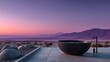 © horizon - Sleek matte black bathtub placed outdoors in a desert landscape at sunset with pastel pink and purple sky and mountains in the distance.