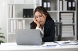 © Wasan - Young Asian businesswoman is bored and tired while using laptop computer in office, looking at the screen with a discouraged expression.