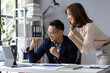 © Wasan - Two happy business colleagues are celebrating a successful project while looking at a tablet in a modern office, raising their arms in excitement and smiling.