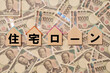 © 洋 奥山 - 住宅ローンの文字と家形のプレートと敷き詰められた一万円札