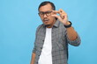 © ArvStd - Asian man holding something small with his fingers, winking, standing isolated on blue background.