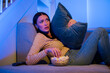 © Home-stock - Scared woman watching terror movie in the night, sitting on couch with bowl of popcorn and hugging pillow in fear