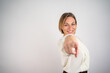 © Nenad - Outgoing carefree woman makes finger pistols, points directly at camera with positive expression, says I choose you, wears casual outfit, stands over grey wall with blank space area. You are my type