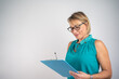 © Nenad - Photo of gorgeous blond secretary woman with short hair writing down notes in clipboard while working in office