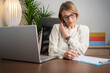 © Nenad - Cheerful mature businesswoman sitting at her workplace