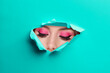 © New Africa - Young woman with beautiful makeup, closeup. View on face through torn hole in turquoise paper