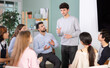 © JackF - Guy stands in front of other students who are sitting in a circle and listening to his speech. Man came to the club of foreign languages