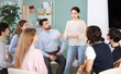 © JackF - Positive young girl talking to attendees of courses sitting in a circle during classes