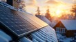 © Alexandr Efimov - A solar panel on a roof with snow on it. The sun is setting in the background. There are two houses in the background