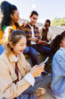 © Xavier Lorenzo - Vertical shot of multiracial youth using smart phone while hanging out in urban street. Gen z asian girl enjoying social media content on phone app