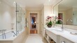 © Jawad Malik - Bathroom of a luxurious house with bathing area from the left side surround by glasses and a silver faucet with white washstand in front of a rectangle shaped mirror, there is an ornamental plant