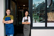 © Westend61 - Bakery employees smiling confidently at door in aprons