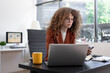 © NanSan - Professional woman using tablet at modern office desk, reviewing documents and business data, representing digital workflow, analysis, productivity, management, planning, corporate efficiency