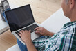 © Westend61 - Man in plaid shirt using laptop on white couch at home in Munich
