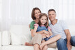 © Westend61 - Family sitting together on white couch smiling in living room