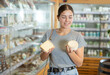 © JackF - Female customer in bio food store holds cheese of different varieties in hands and is thinking about buying. She inspects unfamiliar product in eco supermarket.