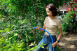© Bluesky60 - Woman watering plants with a garden hose.