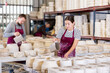 © JackF - Young woman in uniform pours clay from jug into molds for ceramic products at factory