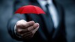 © Jayk - Businessman offering a small red umbrella for protection and security
