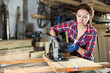 © JackF - Adult woman worker saws oak plank with electric saw in oak workshop