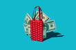 © VISTA by Westend61 - Red heart bag with fan of fake dollar bills on turquoise studio background
