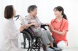 © kapinon - 病院や訪問介護で車椅子の高齢者の患者と家族を看護師が支える全身　在宅やショートステイなど医療の会話するイメージ