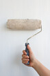 © eza - Hand holding paint roller on white wall background with clipping path