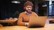 © RZ Images - Middle eastern businessman wearing stylish eyeglasses in headphones, using laptop having video call
