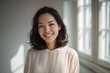 © Mykola - Cheerful Asian woman gazing at the lens with a friendly expression in a neutral studio setting