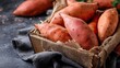 © mila103 - Fresh sweet potatoes in rustic wooden basket on dark background.