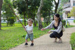 © leungchopan - Mother observing toddler play with stick outdoors