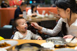 © leungchopan - Mother helping baby eat meal at restaurant