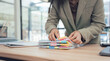 © Nittaya - Organizing Documents: A focused individual meticulously organizes a stack of important documents on a wooden desk. Amidst the organized chaos, the individual sorts through the documents.