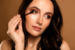 © Beauty Hero - Beautiful young brunette woman applying mascara with a brush, showcasing an elegant and glamorous luxury beauty