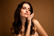 © Beauty Hero - Gentle brunette woman with flawless makeup and styled hair posing against beige background