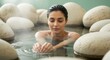 © Anna - Young woman relaxing in a hot spring with steam and large stones. Female person enjoying a thermal spa bath treatment. Wellness and hydrotherapy concept