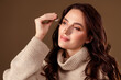 © Beauty Hero - Charming woman in beige sweater applying skincare serum, caring for flawless skin and embracing beauty