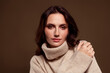 © Beauty Hero - Gentle brunette woman modeling in cozy winter sweater with soft fabrics against warm gradient background