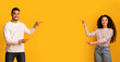 © Prostock-studio - Best Offer. Cheerful Middle-Eastern Couple Pointing At Copy Space In The Middle, Joyful Young Arab Man And Woman Demonstrating Free Place For Your Advertisement On Yellow Background, Panorama