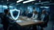© Fitriyani - A glowing shield symbol floats above a blurred business meeting, representing data protection