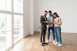 © Prostock-studio - Millennial Couple Buying New Apartment, Standing In Empty Room, Professional Real Estate Agent In Suit Showing Digital Tablet With Build Project, Discussing House Plan, Selling Flat To Happy Family