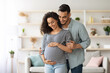 © Prostock-studio - Loving middle-eastern young man husband hugging his beautiful pregnant wife big tummy, millennial arabic family waiting for baby, home interior, copy space. Family, childbirth, pregnancy concept