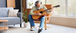 © Pixel-Shot - Mature man in headphones playing guitar at home