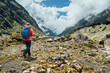 © Soloviova Liudmyla - Woman with backpack and trekking poles dressed red softshell jacket during Makalu Barun National Park trek in Nepal. Mountain hiking and active people concept