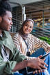 © Jovo Jovanovic/Stocksy - Young adults with devices sit and smile outdoors.