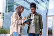 © Jovo Jovanovic/Stocksy - Two young professionals review a tablet in front of building.