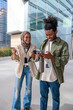 © Jovo Jovanovic/Stocksy - Two young professionals smiling, using phone outside