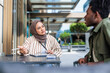 © Jovo Jovanovic/Stocksy - Two people in discussion at an outdoor table.