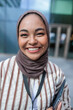 © Jovo Jovanovic/Stocksy - Smiling woman in hijab with striped shirt and tablet.